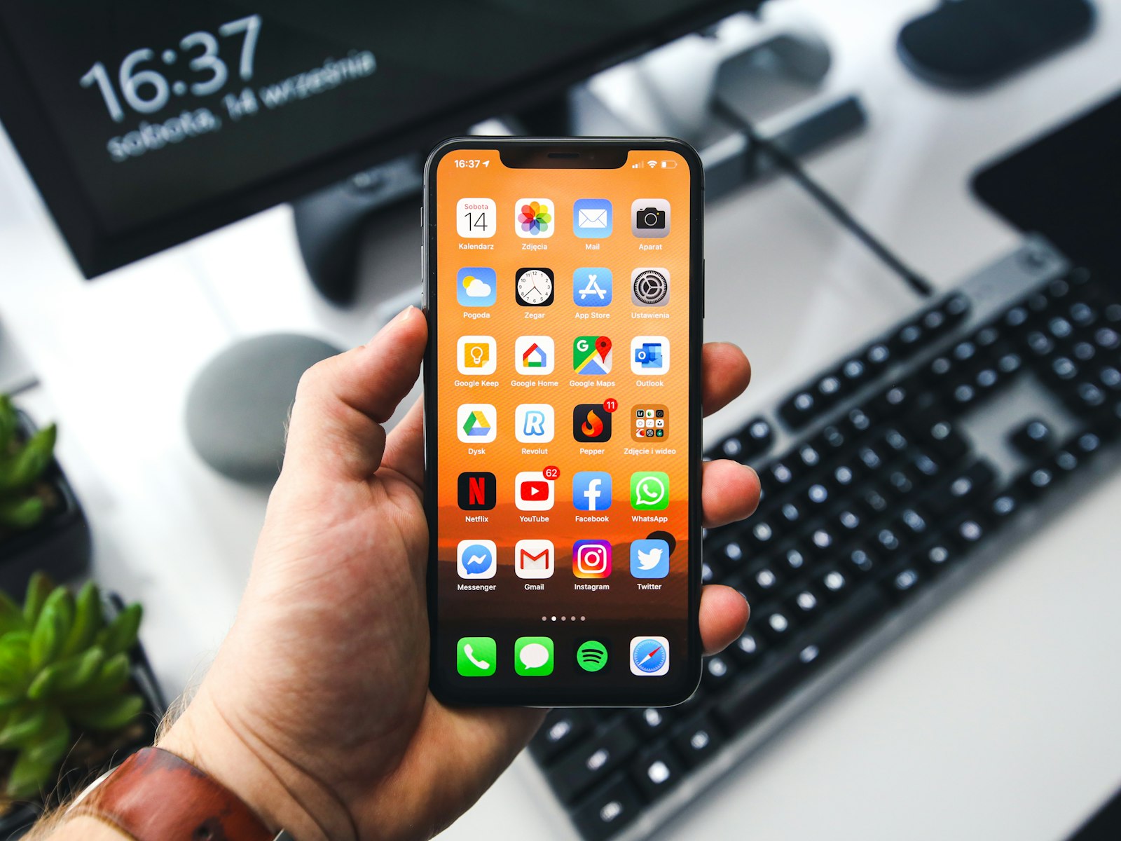 Placeholder photo: a hand holding an iPhone over a keyboard