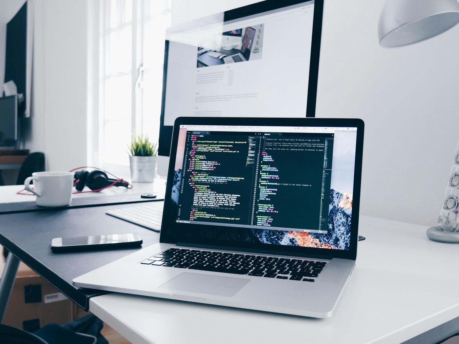 Placeholder photo: a MacBook on a white desk with code on screen