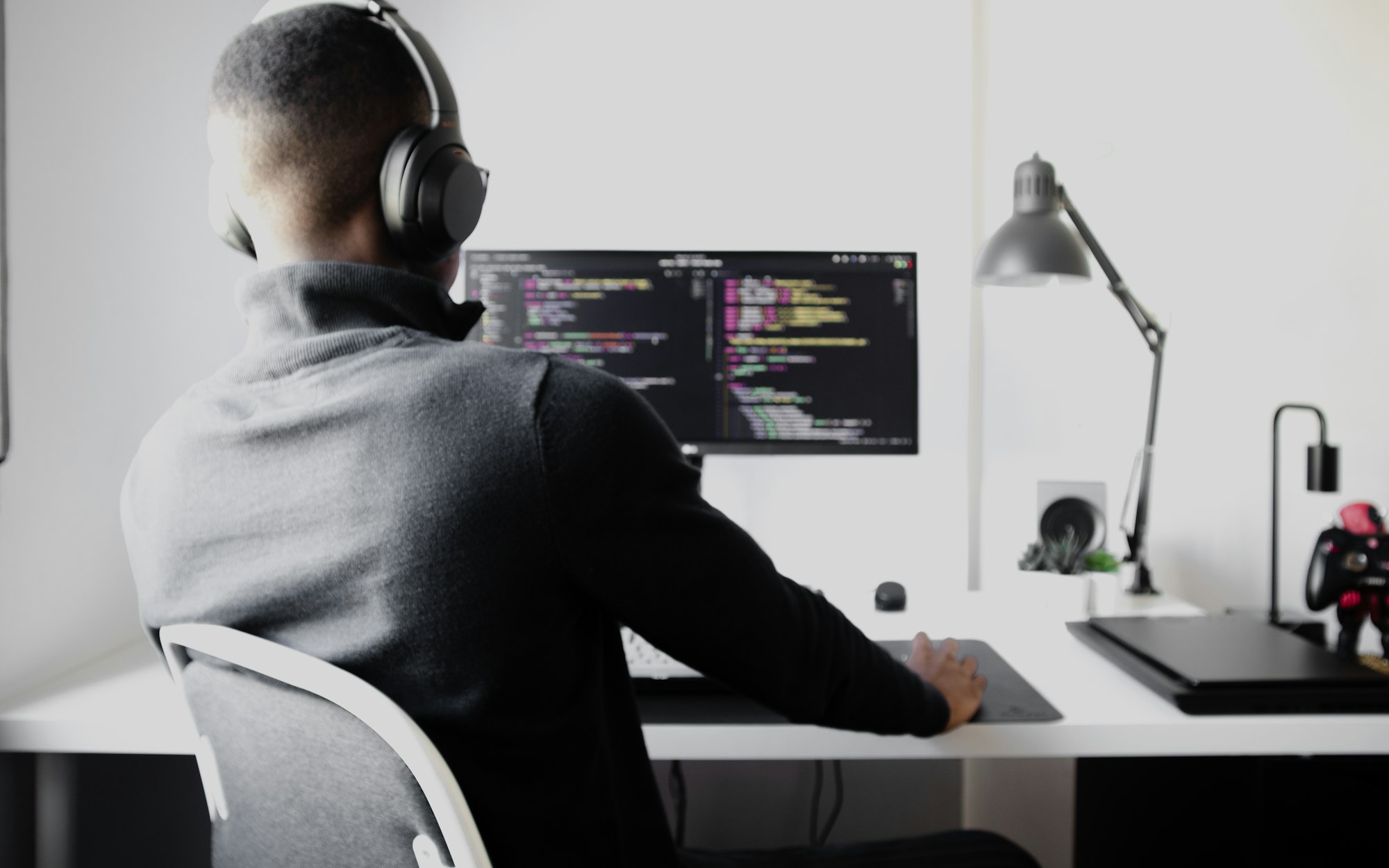 Placeholder photo: over the shoulder of a developer at a desktop monitor full of code